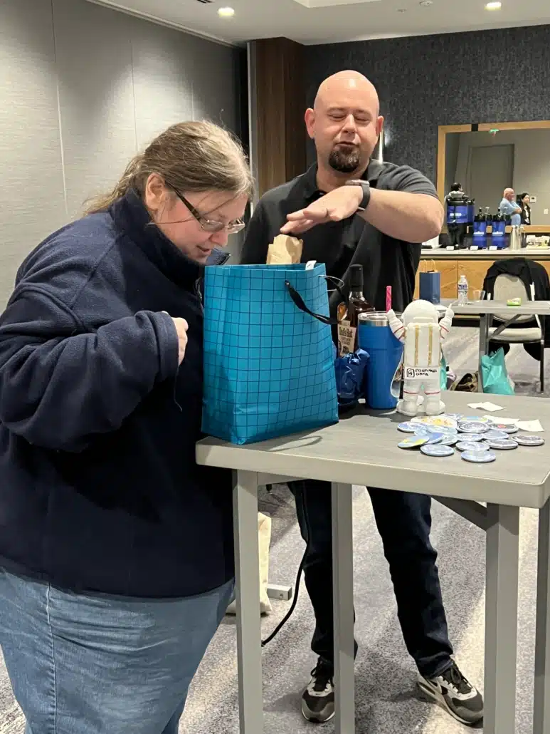 Two colleagues at a table unpacking a gift bag of Fortified Data branded items at a team event.