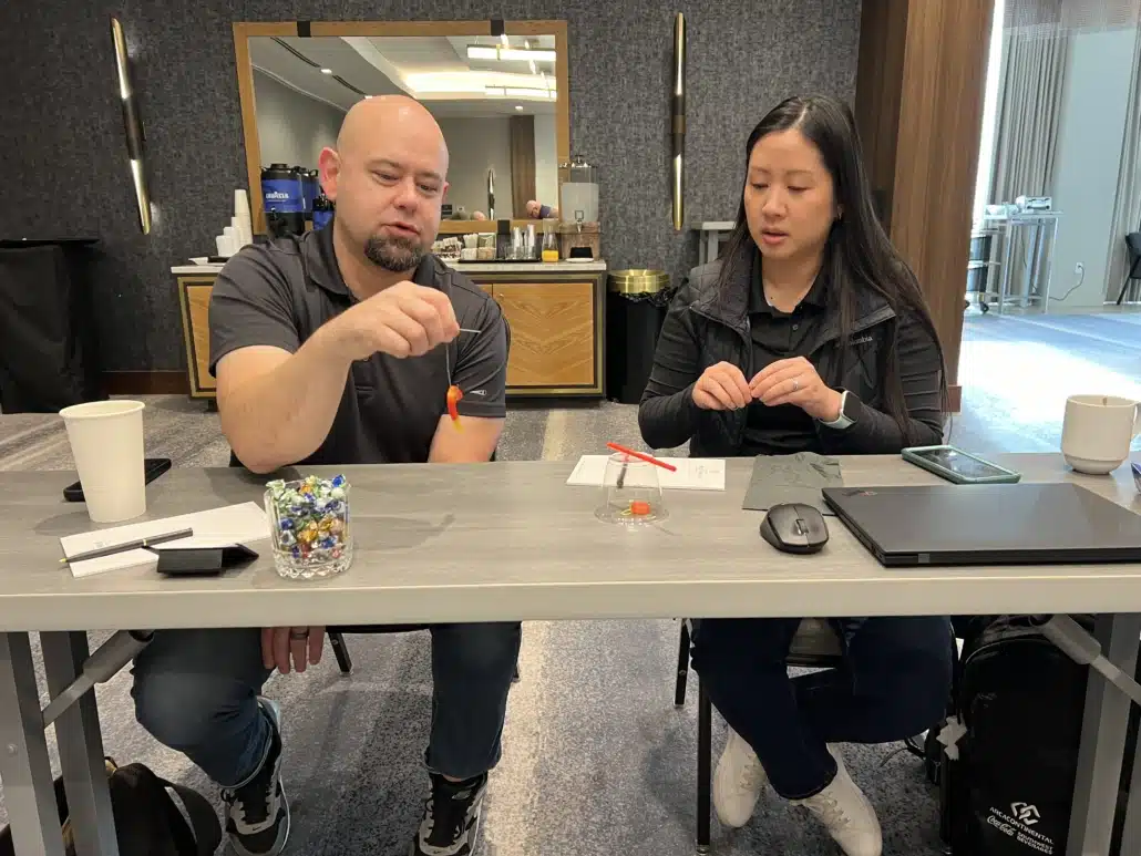 Two colleagues at a meeting room table part way through a hands-on problem-solving exercise.